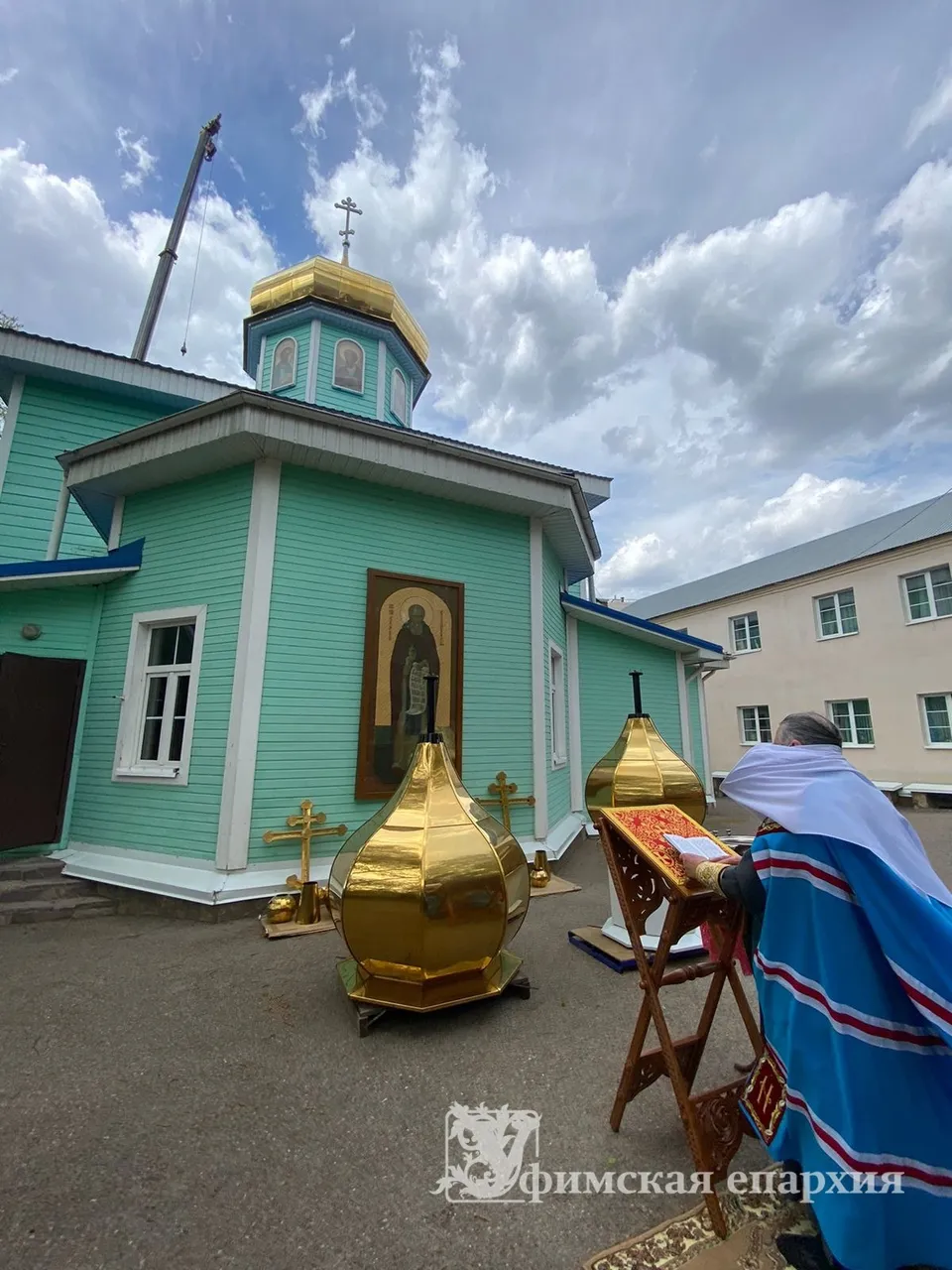 Освящённые золочёные главки с крестами на фоне бирюзового здания собора