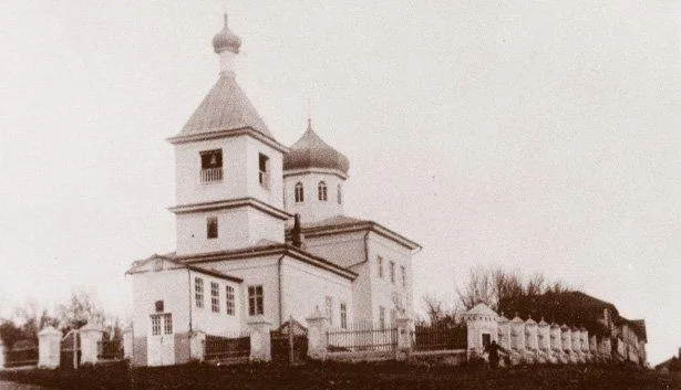 Чёрно-белая фотография деревянной церкви начала XX века с оградой